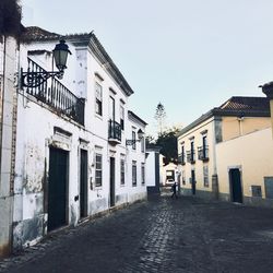 Footpath amidst buildings in town against sky