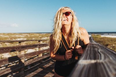 Young woman wearing sunglasses standing against clear sky