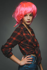 Portrait of beautiful young fashion model with wig against gray background