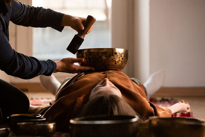 Woman making relaxing massage, meditation, sound therapy with tibetian singing bowls. stress relief