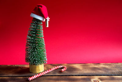 Close-up of christmas decoration on table against red wall