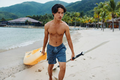 Full length of shirtless man exercising on beach