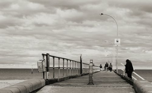 Pier on sea against cloudy sky