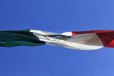 Low angle view of mexican flag against clear blue sky