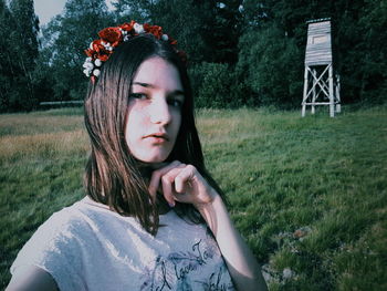 Portrait of young woman wearing tiara standing on grassy field at park during sunset