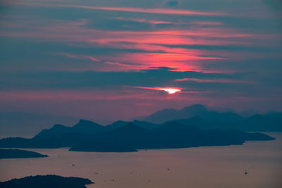 Scenic view of dramatic sky over silhouette mountains during sunset