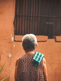 Rear view of boy standing against wall