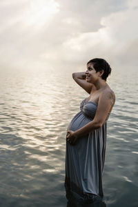 Side view of young woman looking at sea against sky