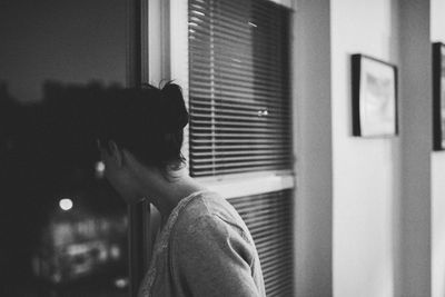 Side view of woman looking out though window at night