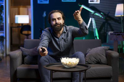 Young man using mobile phone while sitting on sofa at home