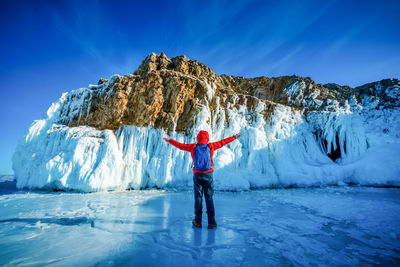 Man standing on snow covered against blue sky