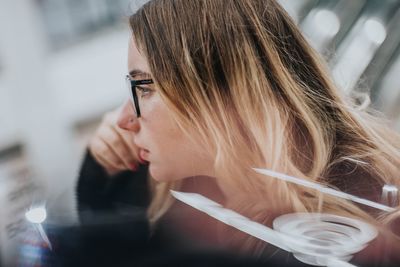 Profile view of thoughtful young woman wearing eyeglasses