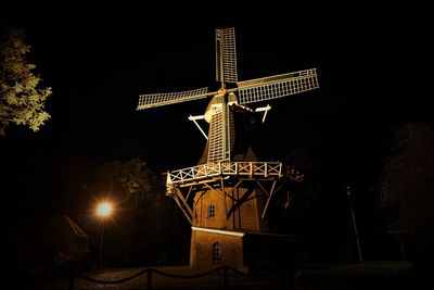 Low angle view of illuminated traditional windmill against sky at night