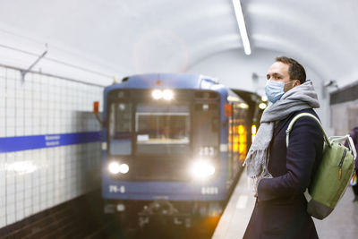 Ill man feeling sick, wearing protective mask against transmissible infectious diseases at subway