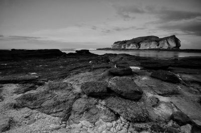 Rock formation on beach against sky