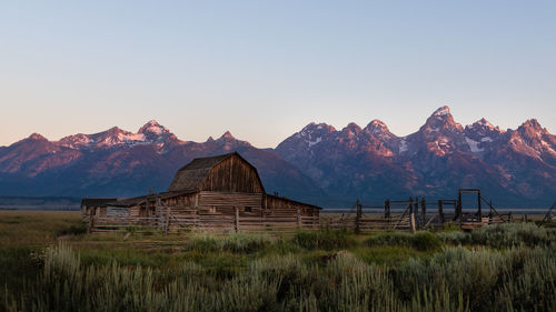 Built structure on field against mountain range against clear sky