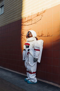 Female astronaut in space suit standing near wall during sunset