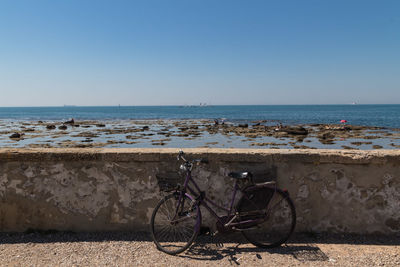 Bicycle by sea against clear sky
