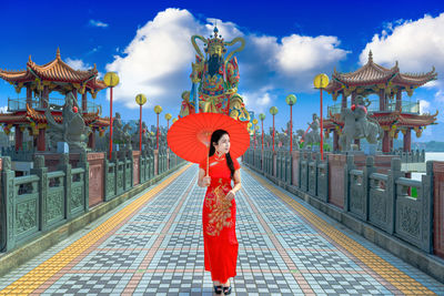 Woman standing on red structure against cloudy sky
