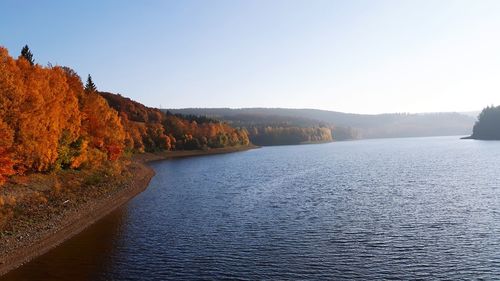 Scenic view of river by mountains against clear sky