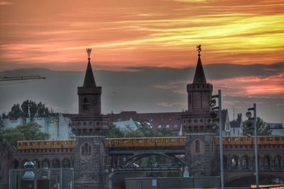 Silhouette of city against cloudy sky at sunset