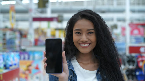 Portrait of smiling young woman using smart phone outdoors