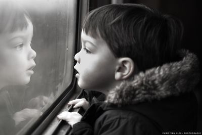 Portrait of cute boy looking through window