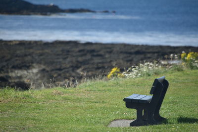 Empty bench on field looking out at the sea