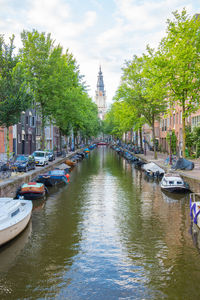 Boats moored in canal amidst buildings in city