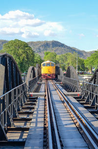 Railroad tracks by bridge against sky