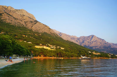 Scenic view of lake by mountains against clear sky