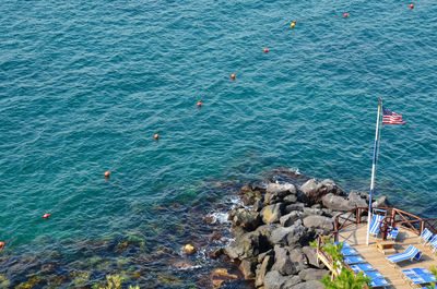 High angle view of american flag on pier by turquoise sea