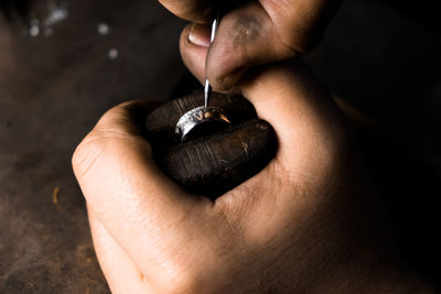 Close-up of hand of a goldsmith setting the diamond on the ring. craft jewelery 
