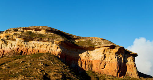 Low angle view of rock formation against clear blue sky