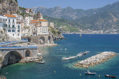 Buildings by sea against mountains