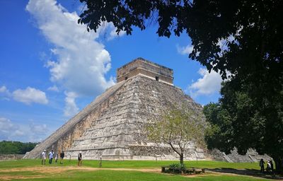 People walking by pyramid against sky