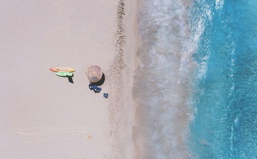 Aerial view of a beach with an umbrella and two surfboards