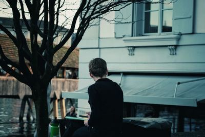 Rear view of boy sitting by water