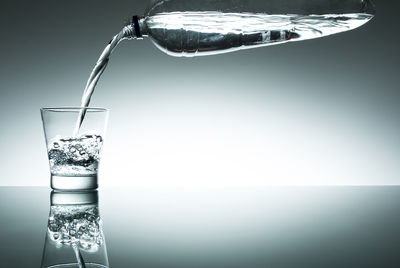 Drinking glass in water against white background