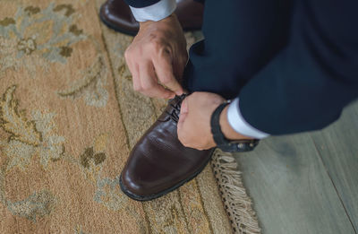 Close-up high angle view of man tying shoelace