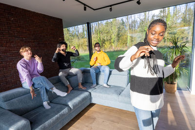 Portrait of smiling friends using digital tablet while sitting on sofa at home