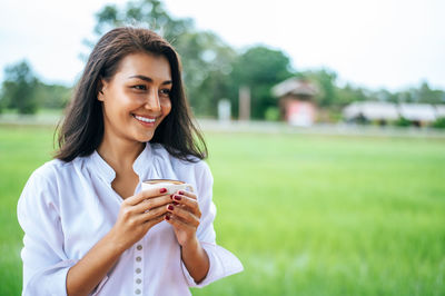 Portrait of smiling young woman drinking coffee