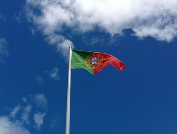 Low angle view of portuguese flag against blue sky