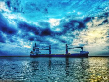 Ship moored on sea against cloudy sky