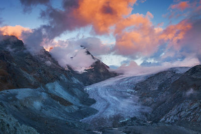 Scenic view of swiss alps against cloudy sky during sunset