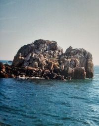 Rock formation in sea against clear sky