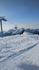 Ski lift over snow covered field against sky