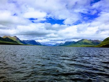 Scenic view of sea by mountains against sky