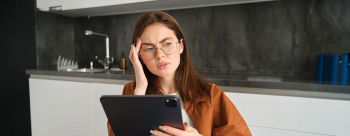 Young woman using mobile phone while sitting on table