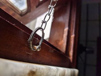 Close-up of chain hanging on wood at home